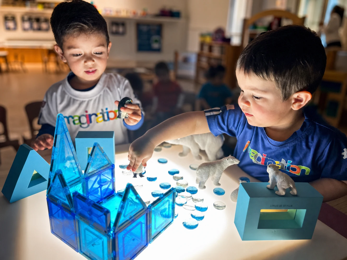 Two children building with translucent magnetic tiles