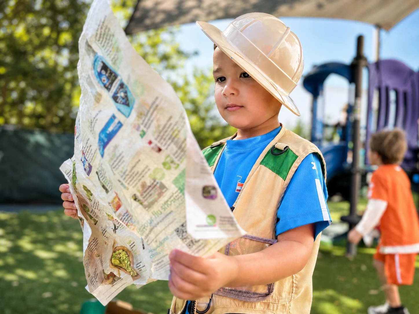 A child in a hard hat studying a map outdoors
